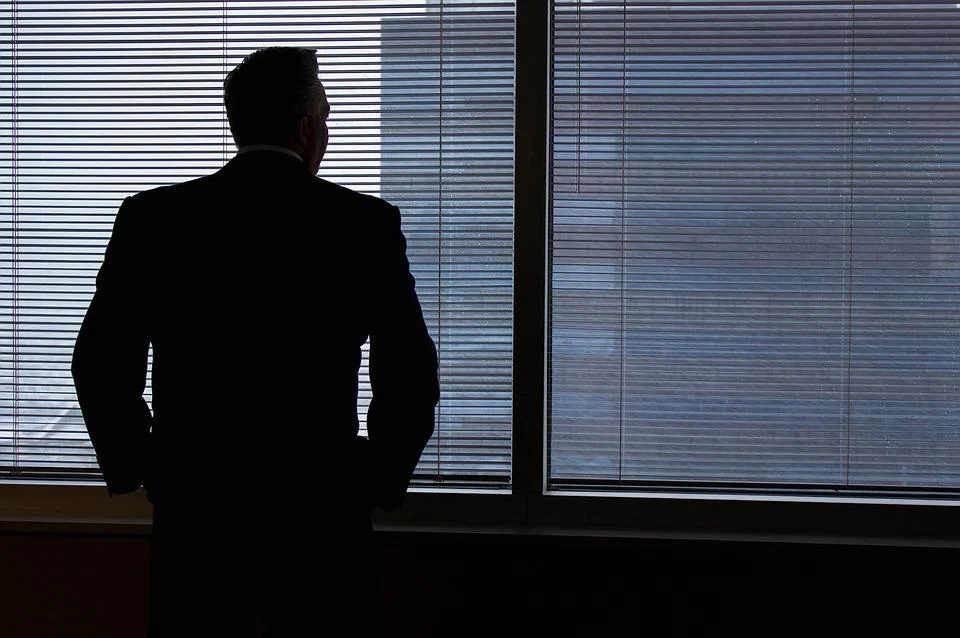Na imagem, silhueta de homem de negócios olhando pela janela (Foto: Mhouge/Pixabay)