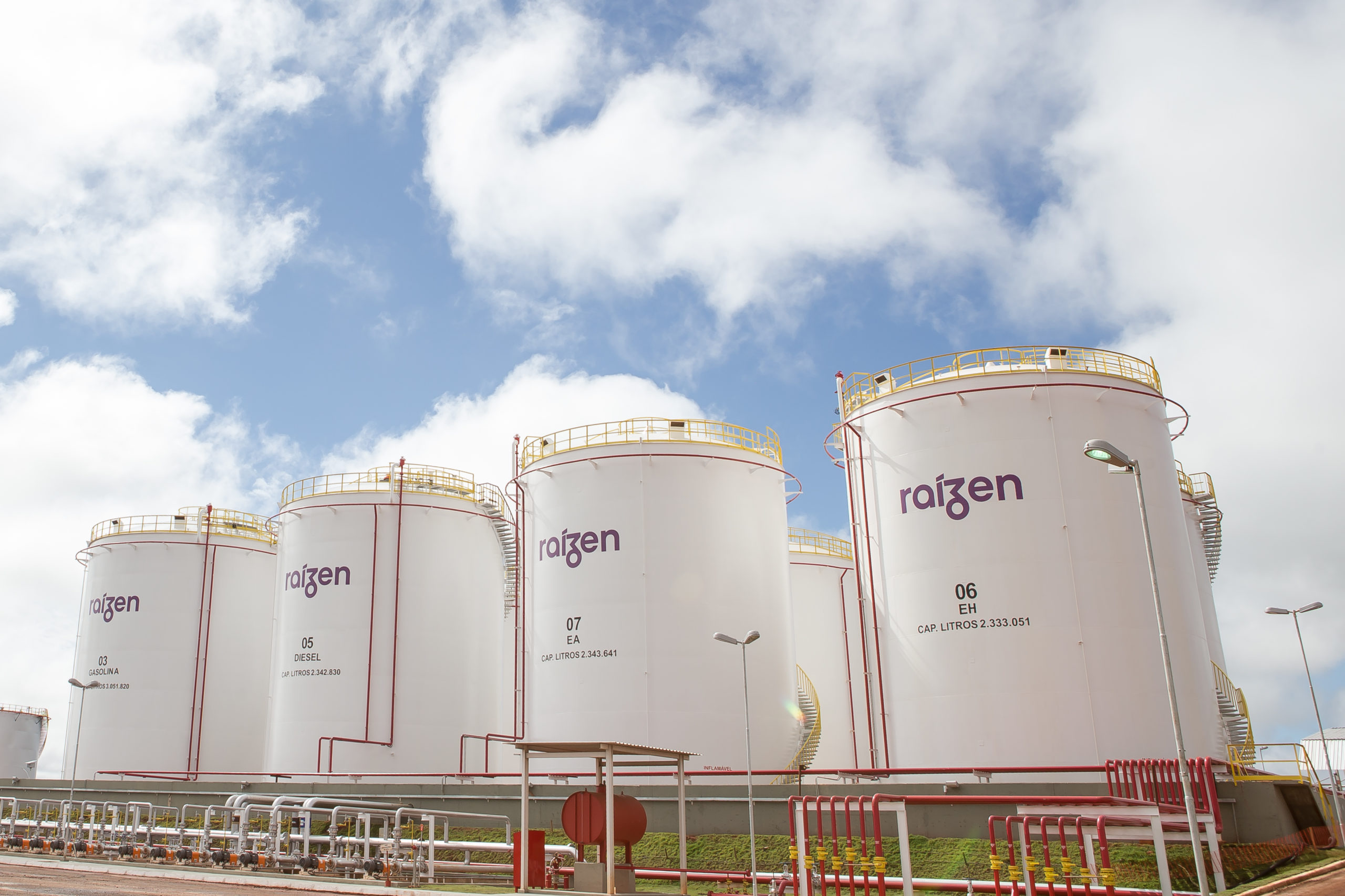 Shell fecha acordo de compra de 3,25 bilhões de litros de etanol 2G da Raízen. Na imagem: Dutos e tanques de armazenamento de biocombustíveis imensos, na cor branca, com a inscrição "Raízen", na base de combustíveis em Rondonópolis, no Mato Grosso (Foto: Divulgação Raízen)
