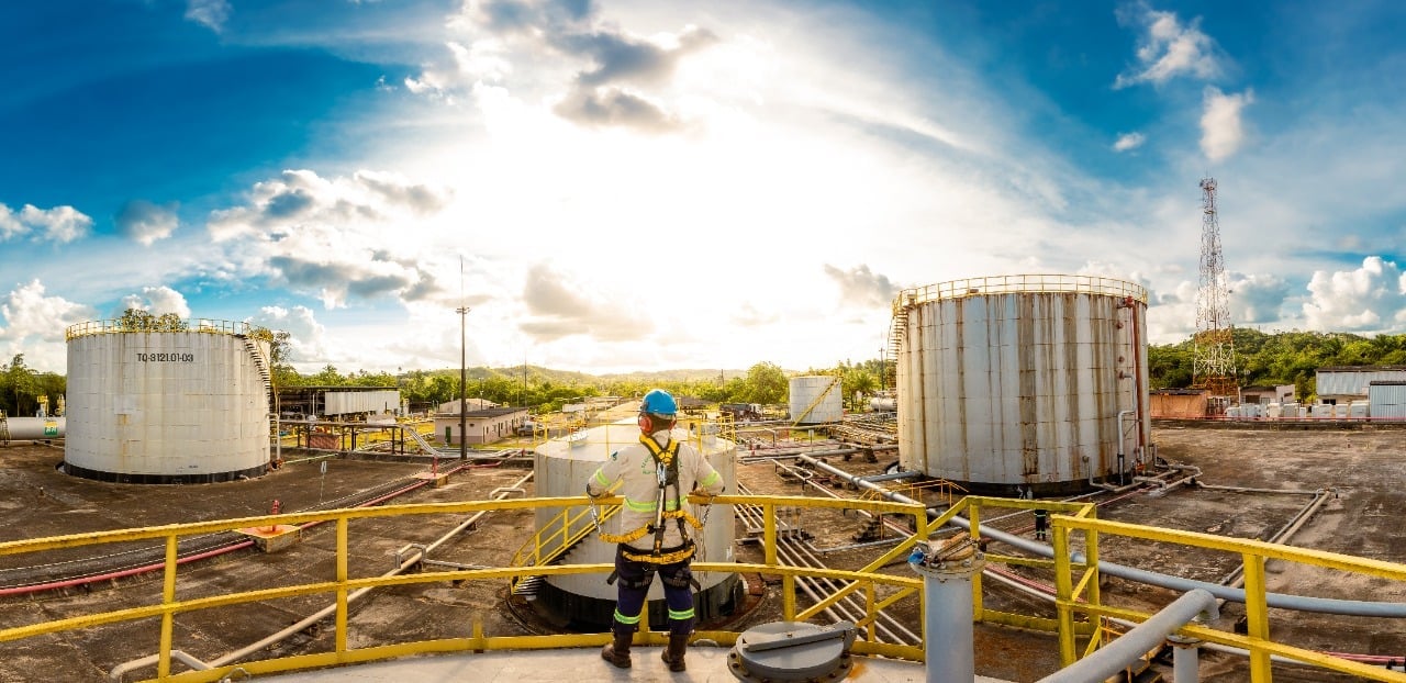 PetroReconcavo compra Maha Energy por US$ 138 milhões. Na imagem: Operação da PetroRecôncavo no Polo Miranga, na Bahia; Trabalhador, com equipamentos de segurança, observa a planta, do alto, e encostado em parapeito amarelo (Foto: Cortesia PetroRecôncavo)