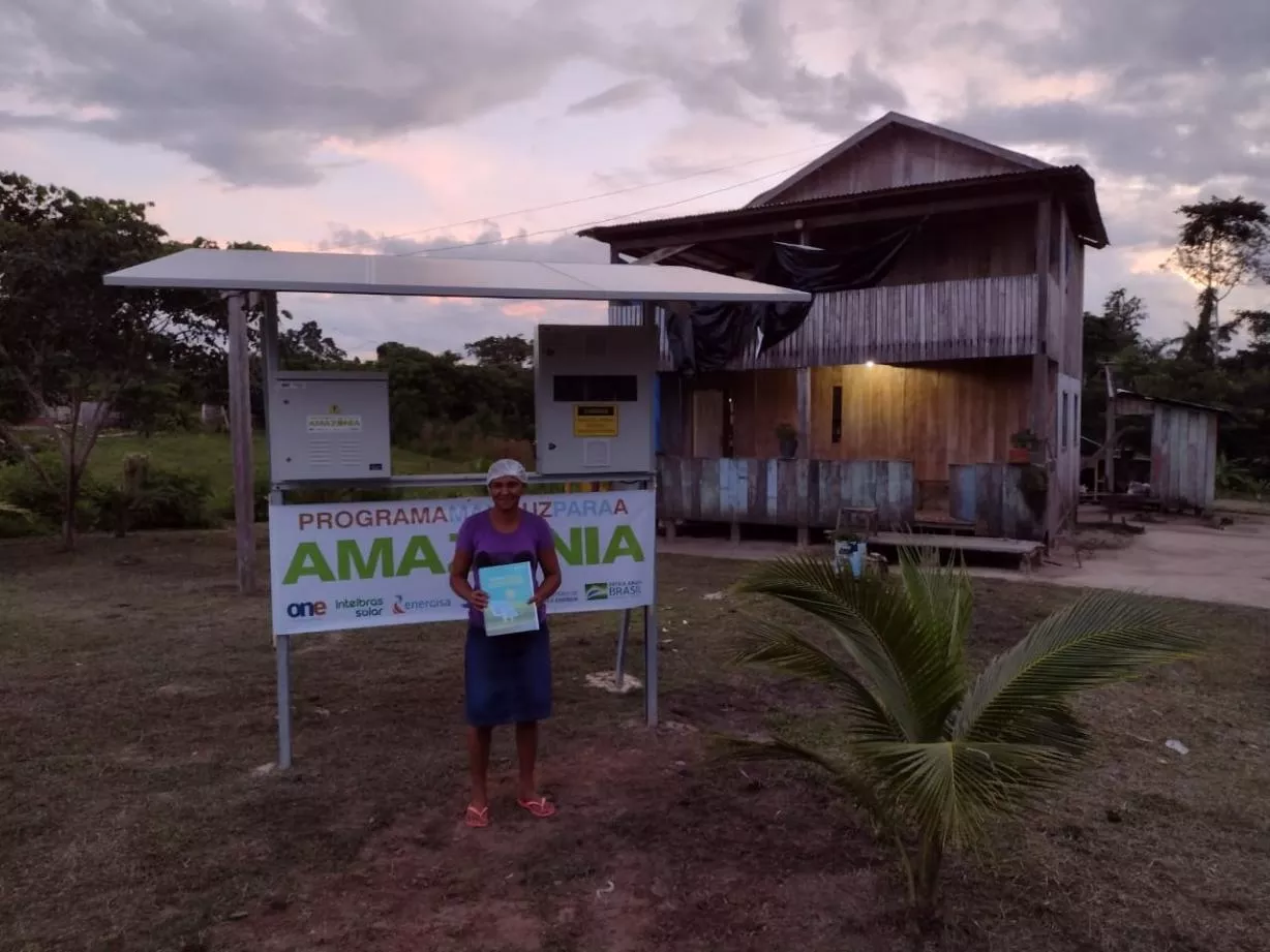 Na imagem: Mulher segura conta de luz e sorri. Programa Mais Luz Para a Amazônia leva energia elétrica a comunidades em áreas remotas (Foto: Divulgação/Energisa)