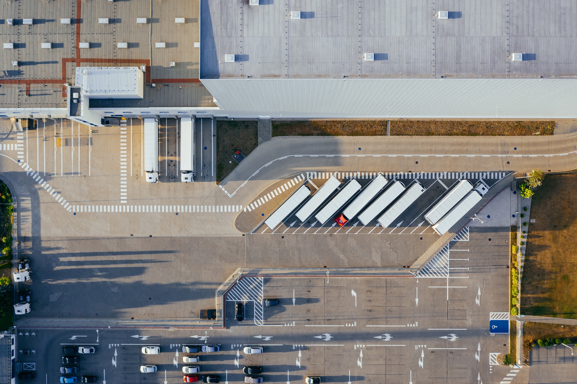 Bayer diversifica mix energético para descarbonizar logística e manufatura. Na imagem: Foto aérea de caminhões estacionados em planta industrial (Foto: Marcin Jozwiak/Pixabay)