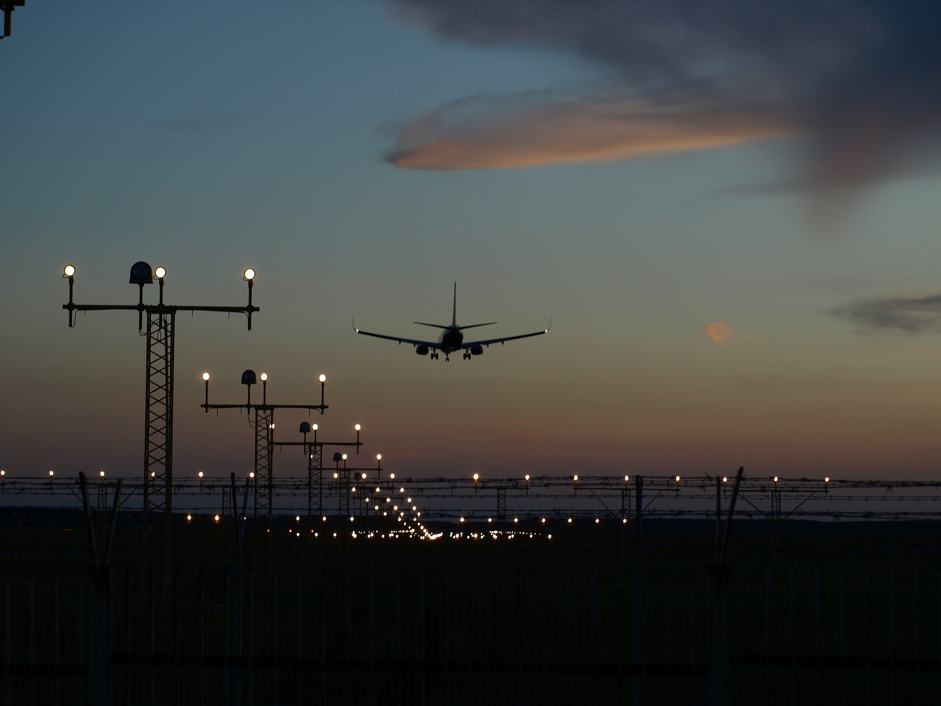 Net zero da aviação pode atrasar cinco anos, indica pesquisa da GE Aerospace. Na imagem: Avião voando ao anoitecer com uma série de postes sinalizadores, à esquerda (Foto: Pixabay)