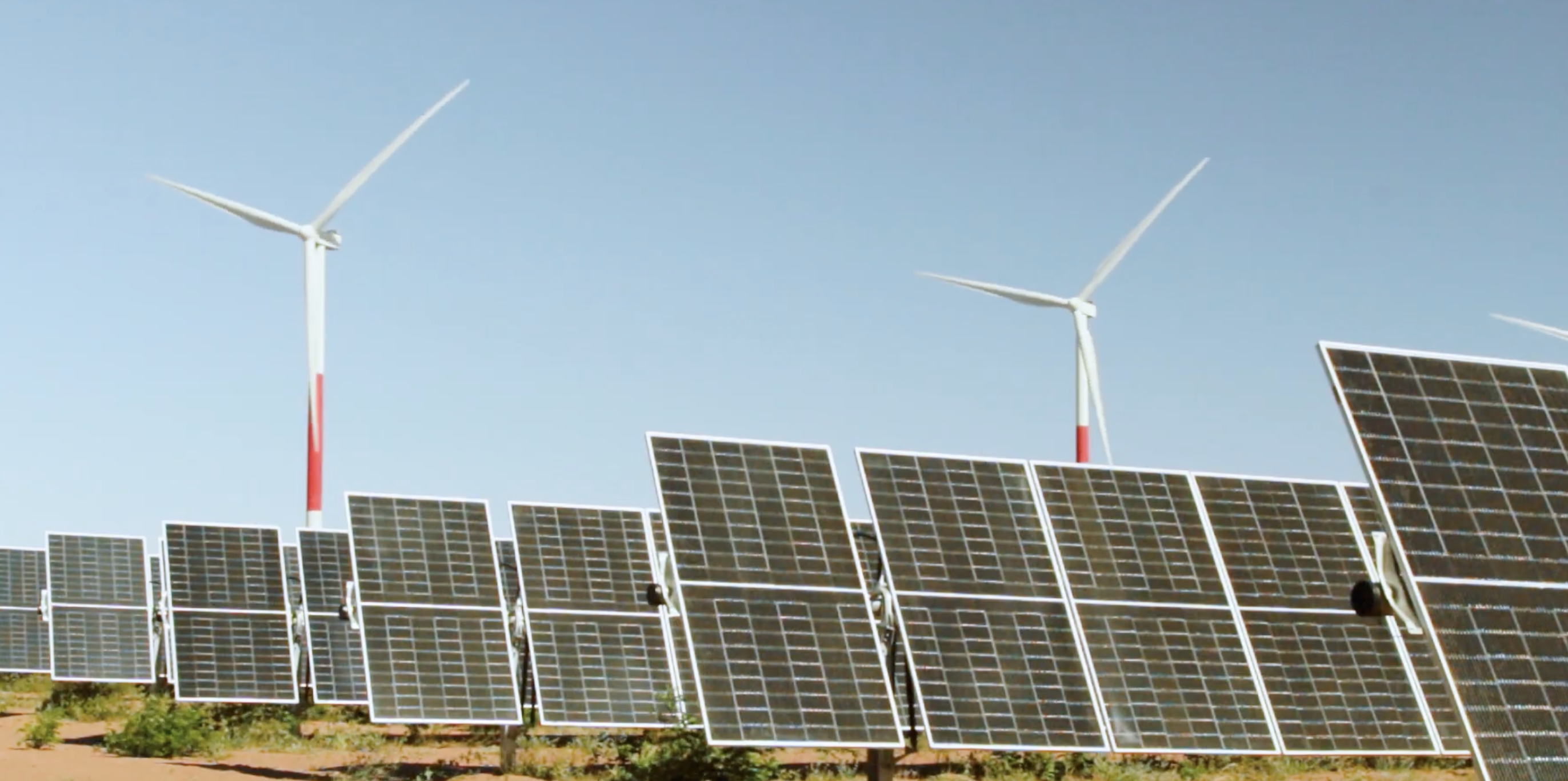 Taxa de crescimento de demanda global por eletricidade deve cair em 2023, projeta IEA. Na imagem: Usina solar fotovoltaica Serra do Mel da Voltalia, com painéis na vertical e turbinas eólicas ao fundo (Foto: Divulgação)