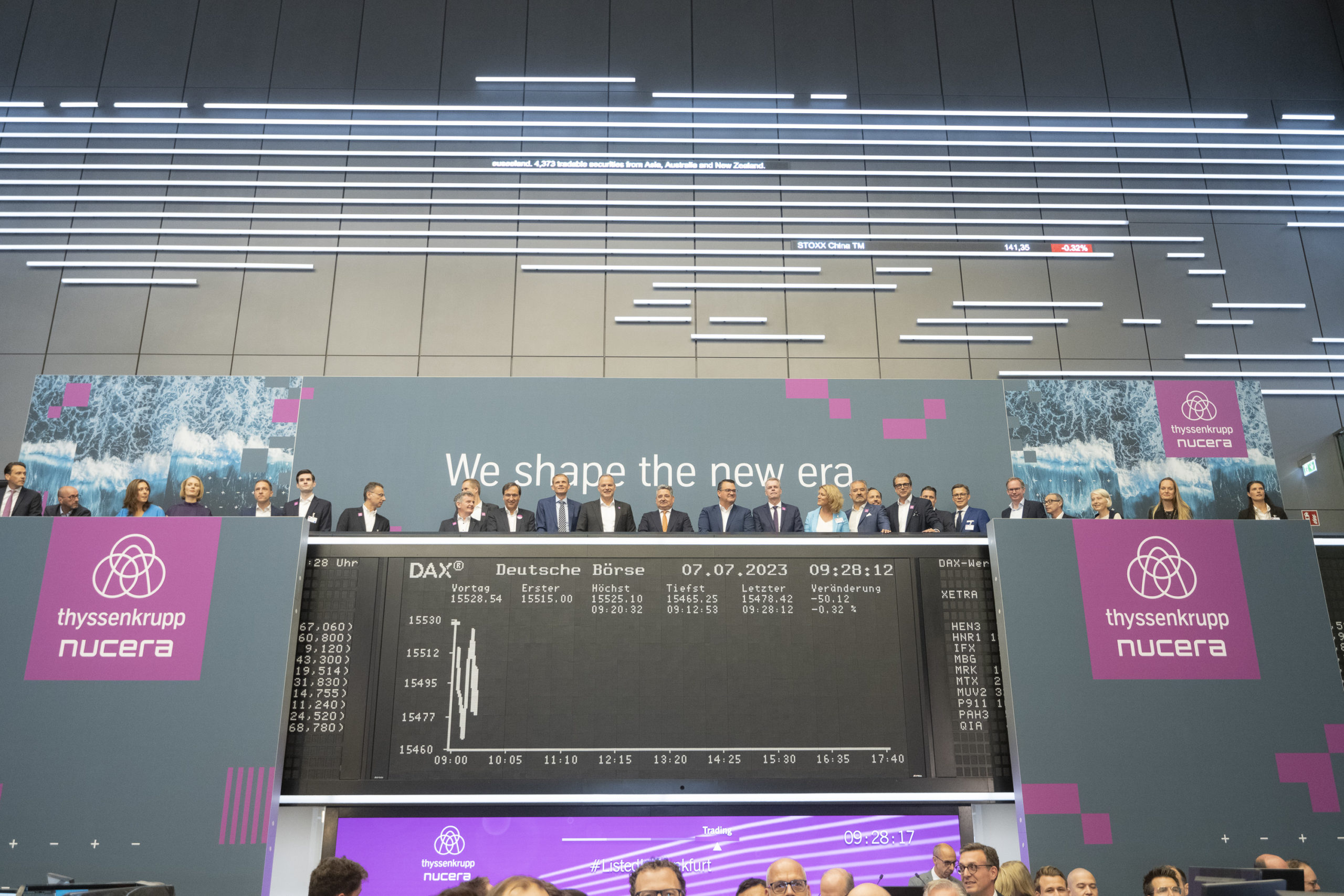 Executivos de terno e gravata, atrás de um balcão, comemoram IPO da thyssenkrupp nucera na bolsa de Frankfurt (Foto: Divulgação)
