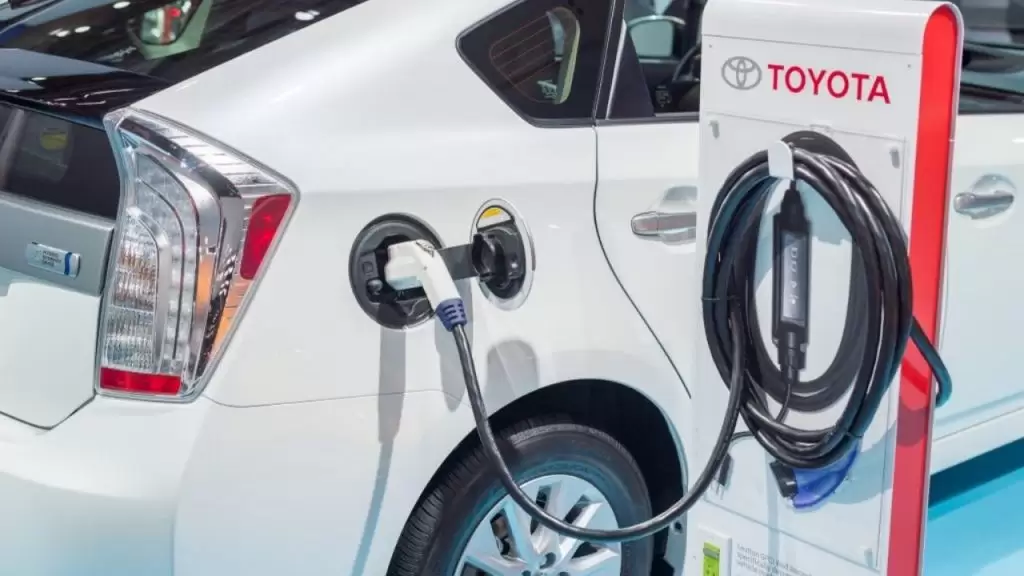 Veículo elétrico da Toyota, na cor branca, conectado a estação de carregando (Foto: Divulgação)