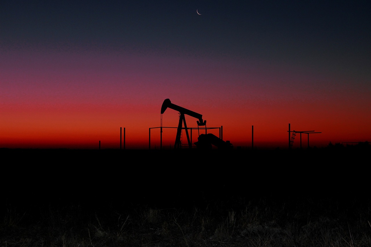Cavalo-de-pau para exploração onshore de petróleo, fotografado ao longe e à contraluz, com céu ao anoitecer em tons do laranja para o roxo (Foto: James Armbruster/Pixabay)