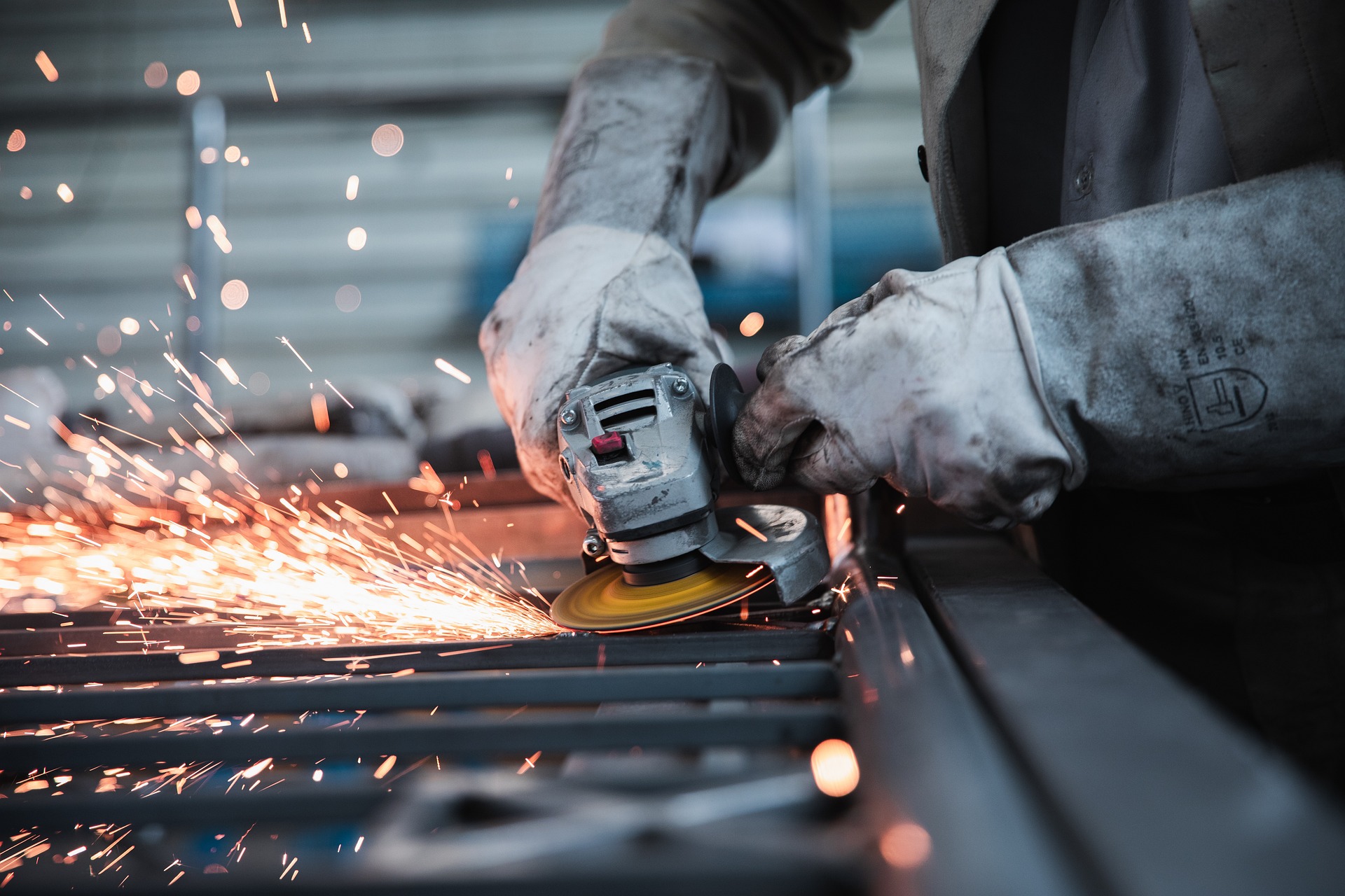 Trabalhador, com equipamentos de proteção individual, esmerilha barras de metal que soltam faíscas incandescentes (Foto: Janno Nivergall/Pixabay)