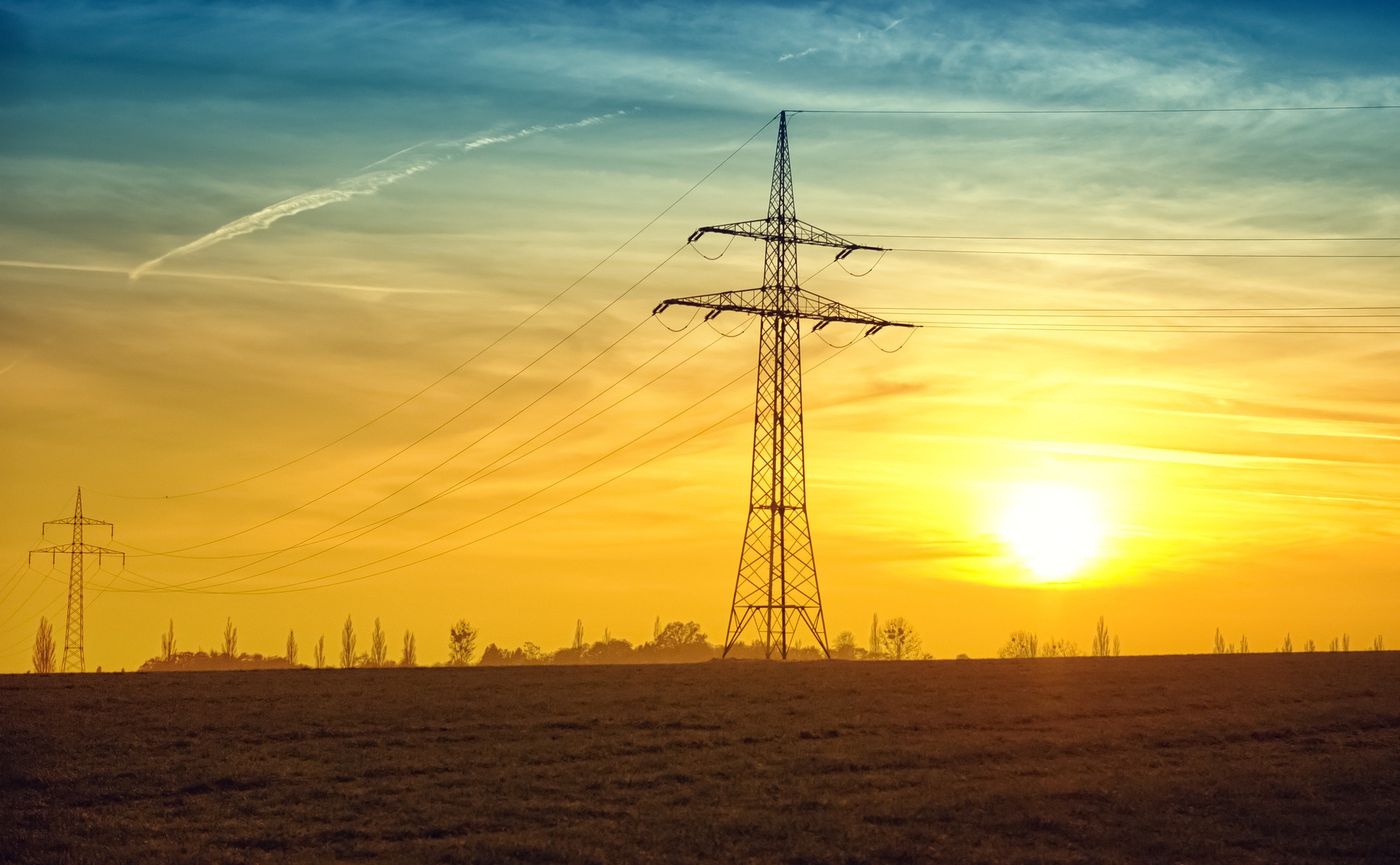 Calor eleva consumo de energia elétrica no Brasil, aponta CCEE. Na imagem: Foto à contraluz de torres com linhas de transmissão de energia elétrica, e pôr-do-sol ao fundo (Foto: Nicole Köhler/Pixabay)