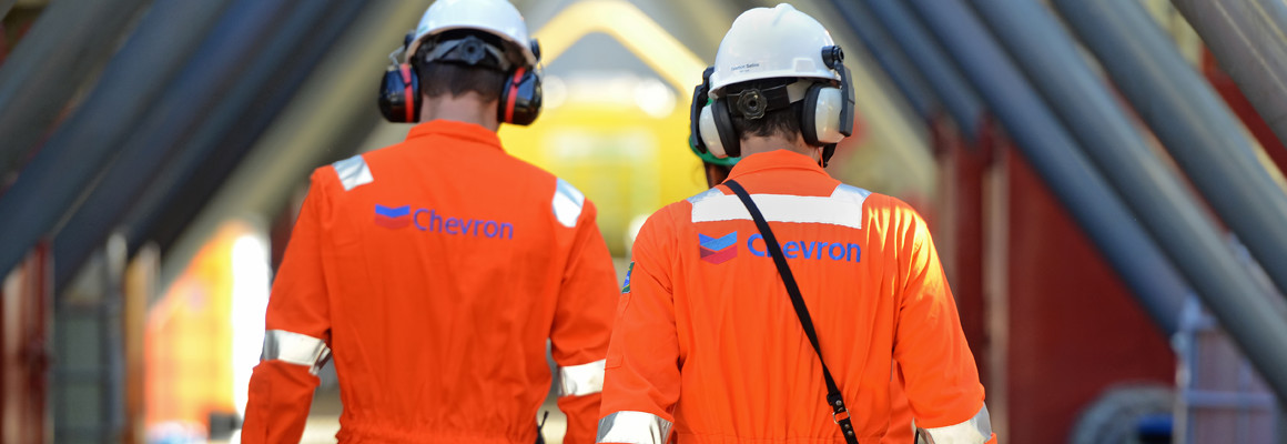 Petroleira Chevron prevê investimentos de US$ 16 bilhões em 2024 e vai concentrar aportes nos Estados Unidos. Na imagem: Trabalhadores em planta da Chevron, nos EUA, com uniformes laranjas e capacetes e protetores auriculares brancos (Foto: Divulgação)