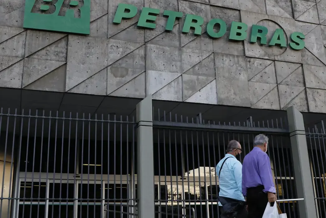 Petrobras registra queda de 33,8% no lucro líquido em 2023, puxada pela redução da receita de vendas e pelo aumento nas despesas operacionais. Na imagem: Dois homens passam em frente à fachada do edifício sede da Petrobras (Edise) na avenida Chile, no centro do Rio (Foto: Fernando Frazão/Agência Brasil)