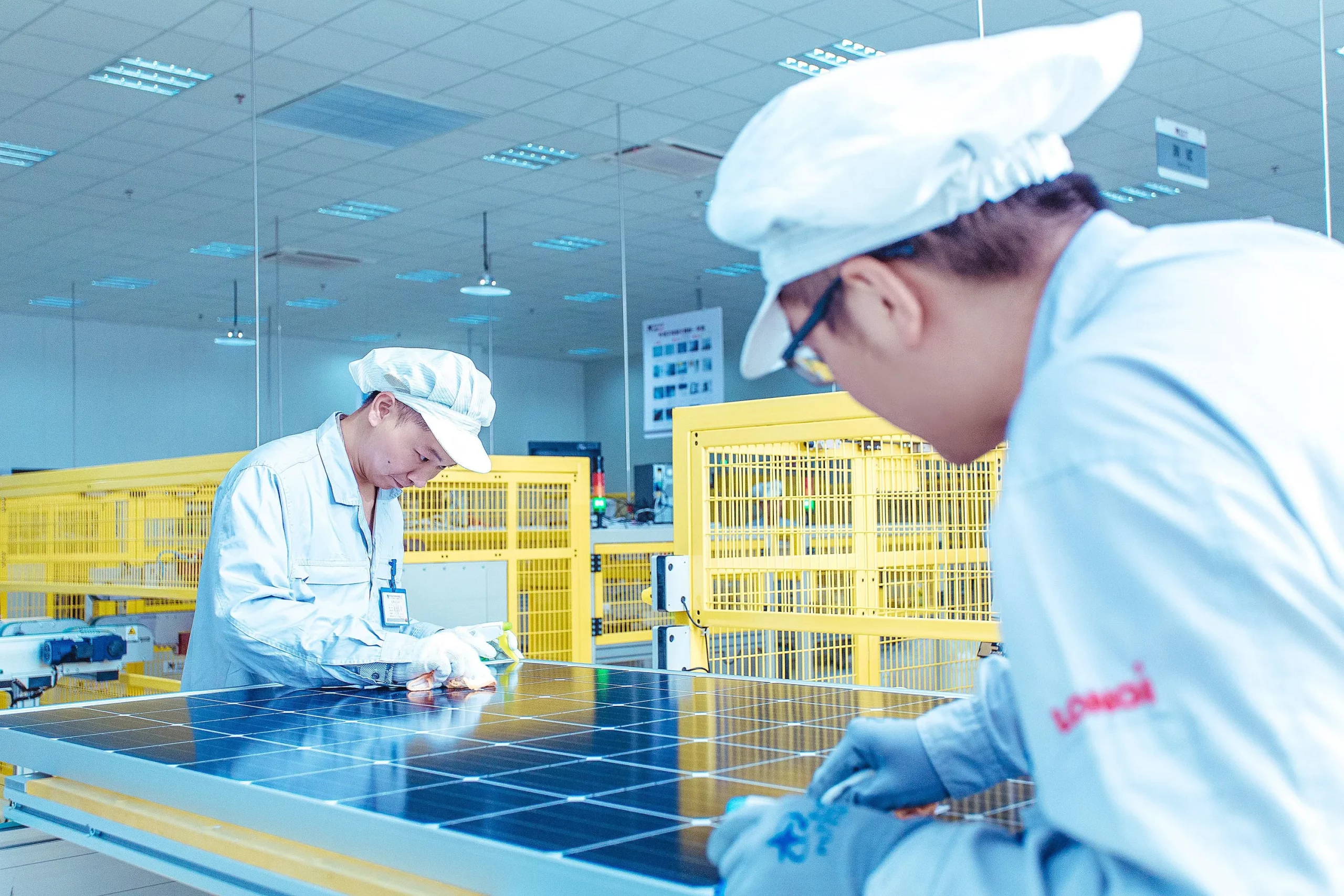 União Europeia lança duas investigações para apurar possíveis subsídios irregulares a fabricantes chineses de painéis solares. Na imagem: Dois trabalhadores de origem asiática realizam testes de painéis solares em fábrica da Longi Solar na China (Foto: Divulgação)